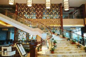 A grand staircase with a geometric patterned wall, multiple levels, and potted plants. - Huaxin Hotel (XIANNING)