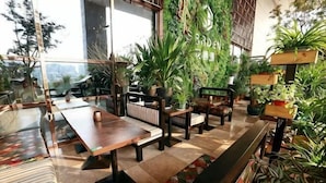 Un espacio interior moderno con mesas, sillas y plantas en macetas.