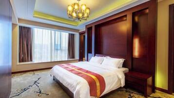 A hotel room with a large bed, a chandelier, a window with curtains, and a wooden headboard.