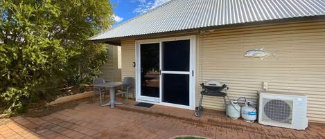 A house with a patio, a sliding glass door, a barbecue grill, and propane tanks.