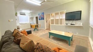 Ein Wohnzimmer mit einer Couch, einem Couchtisch und einem an der Wand befestigten Fernseher.