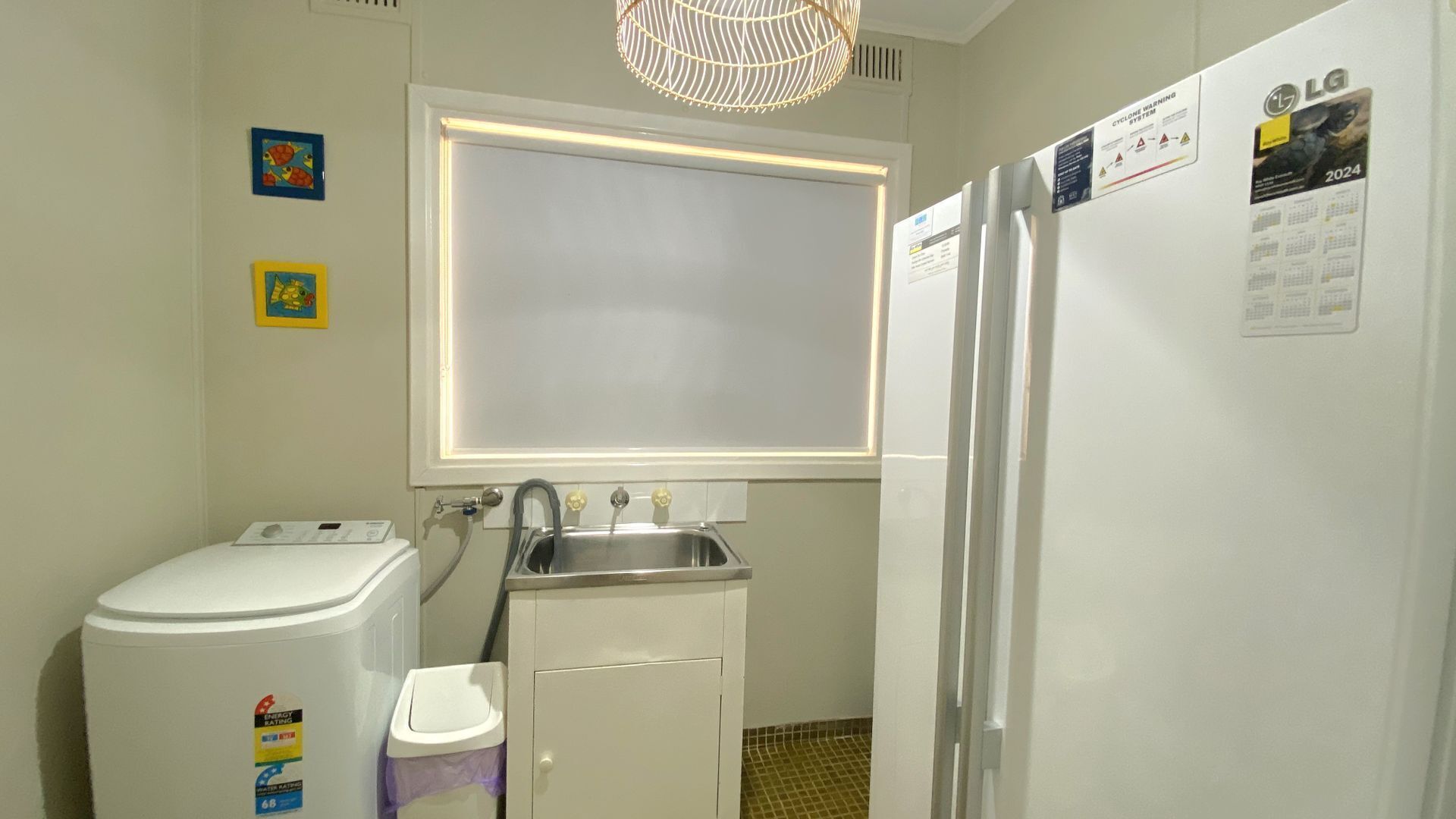 Une cuisine de taille réduite équipée d’un lave-linge, d’un évier et d’un réfrigérateur.