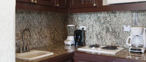 Eine Küche mit Granit-Arbeitsplatten, einem Spülbecken, einer Mikrowelle, einer Kaffeemaschine und einem Kühlschrank.