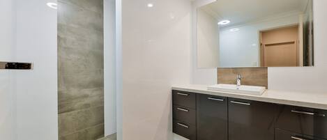 A modern bathroom with a large mirror, a sink, and dark cabinets.