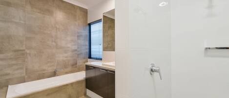 A modern bathroom with a bathtub, a shower, and a toilet.