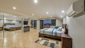 Ein modernes Schlafzimmer mit einem großen Bett, einem Fernseher und einem Balkon mit Blick auf die Stadt.