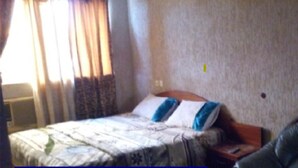 Una habitación de hotel con cama, una silla y una pared alfombrada.
