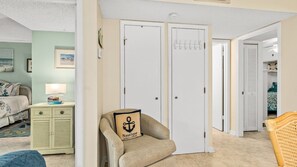 Une chambre à coucher comprenant un lit, une table de chevet, une lampe, une chaise agrémentée d’un coussin à motifs marins, et une armoire avec une porte.