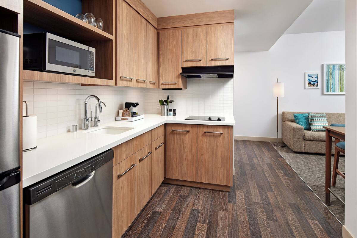 A modern kitchen with wooden cabinets, stainless steel appliances, and a white countertop.