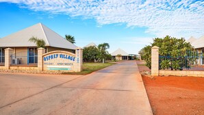 A residential area with a sign for Osprey Village holiday apartments, a paved driveway, and a clear sky. - Osprey Holiday Village Unit  112 - 3 Bedroom Fully Self-Contained Holiday Accommodation (EXMOUTH)