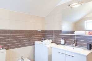 A modern bathroom with a dual sink vanity, a toilet, and a shower area. - Holiday Home Puteus (Selca)