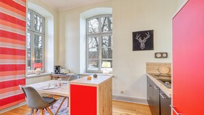 Una cucina moderna con isola centrale, ampie finestre e una parete d'accento rossa.