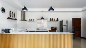 Una cocina moderna con una isla central, luces colgantes y un ventanal grande.