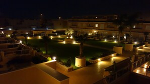 A nighttime view of a hotel courtyard with a swimming pool, palm trees, and outdoor seating areas. - 3027 Vista Azul,close to the beach &  heated pool (Torre de la Horadada)