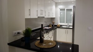 A modern kitchen with white cabinets, a black countertop, and a bottle of wine. - 3027 Vista Azul,close to the beach &  heated pool (Torre de la Horadada)