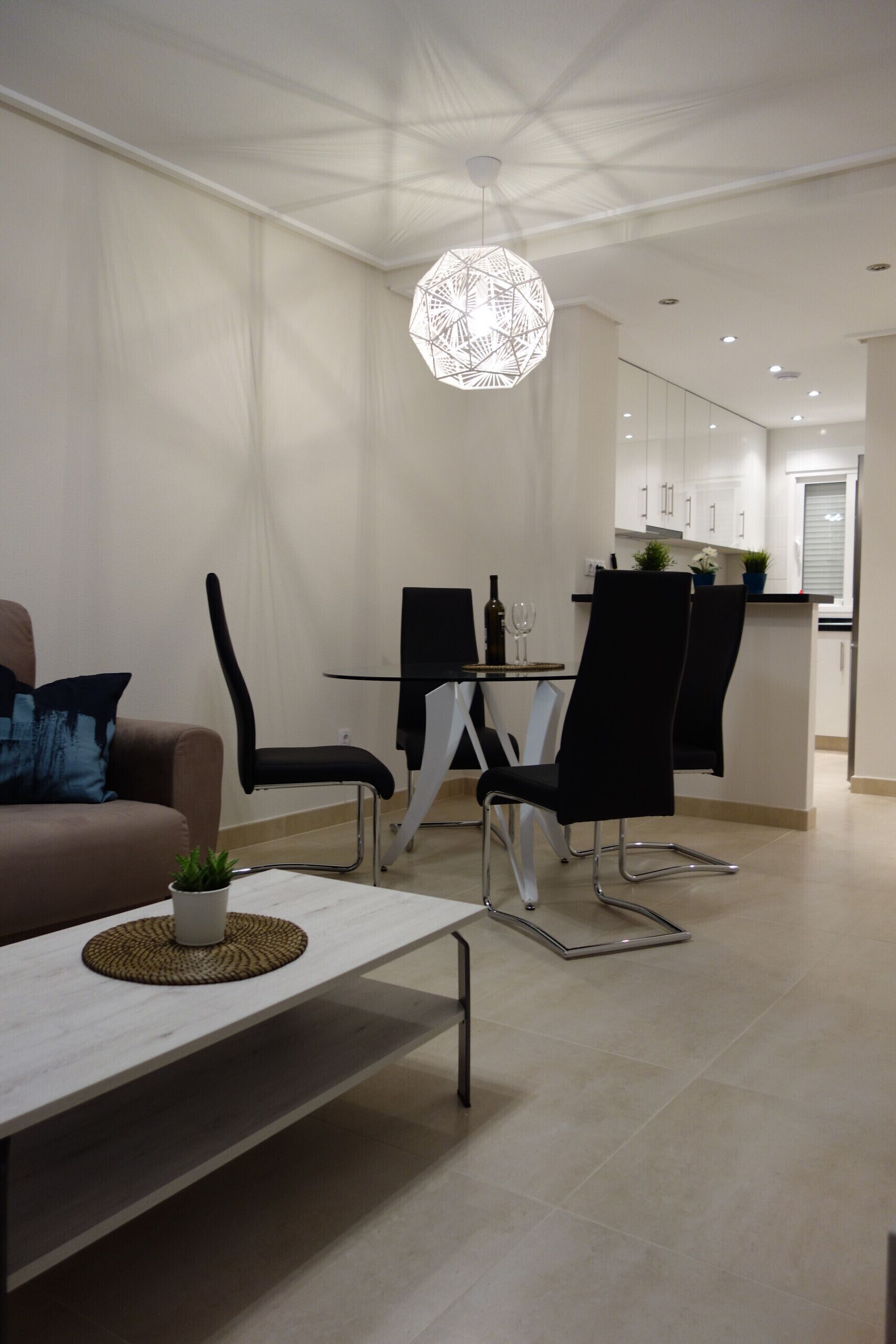 A modern dining area with a table, chairs, and a pendant light.