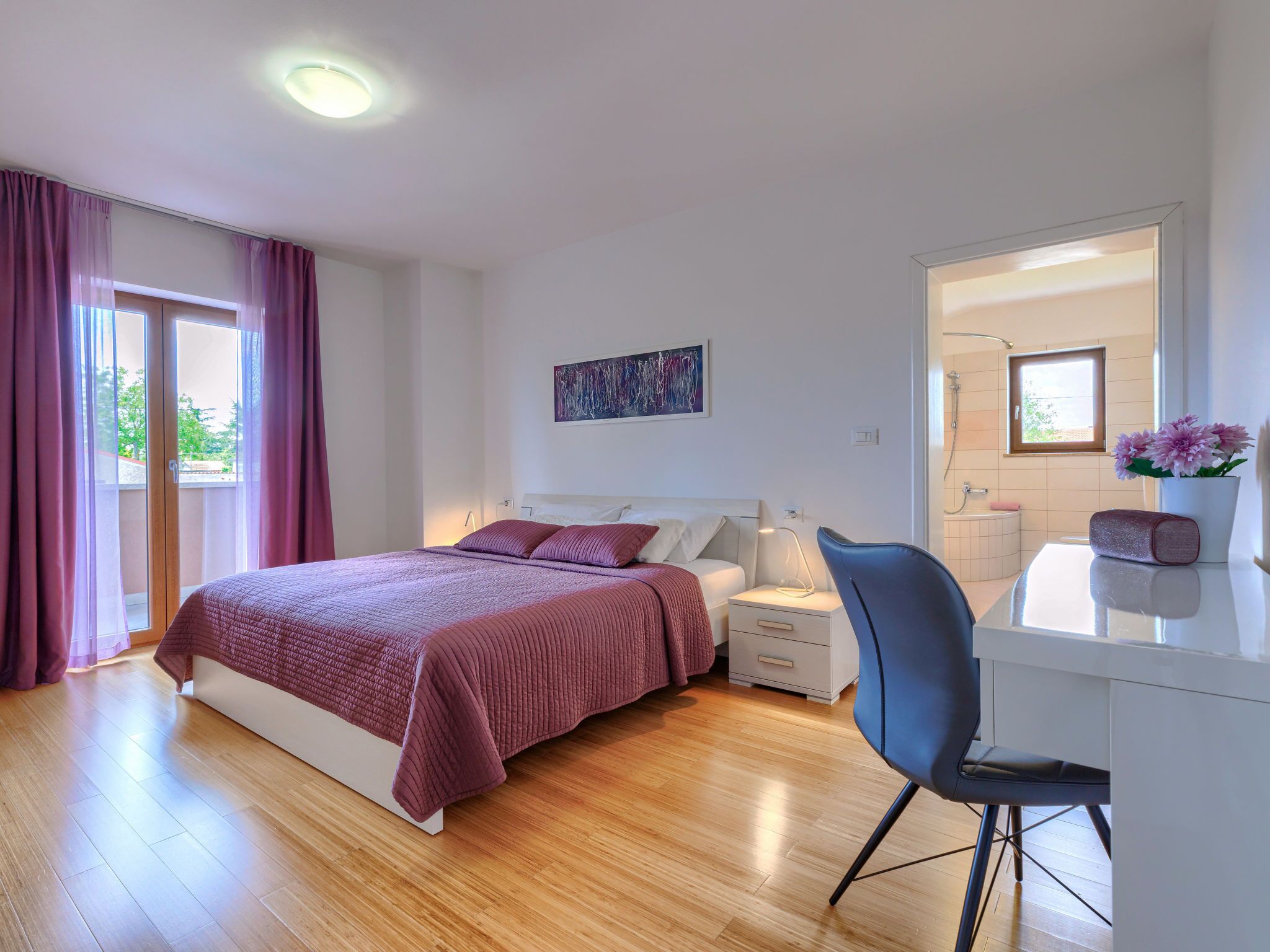 A modern bedroom with a bed, bedside table, chair, and a desk area.