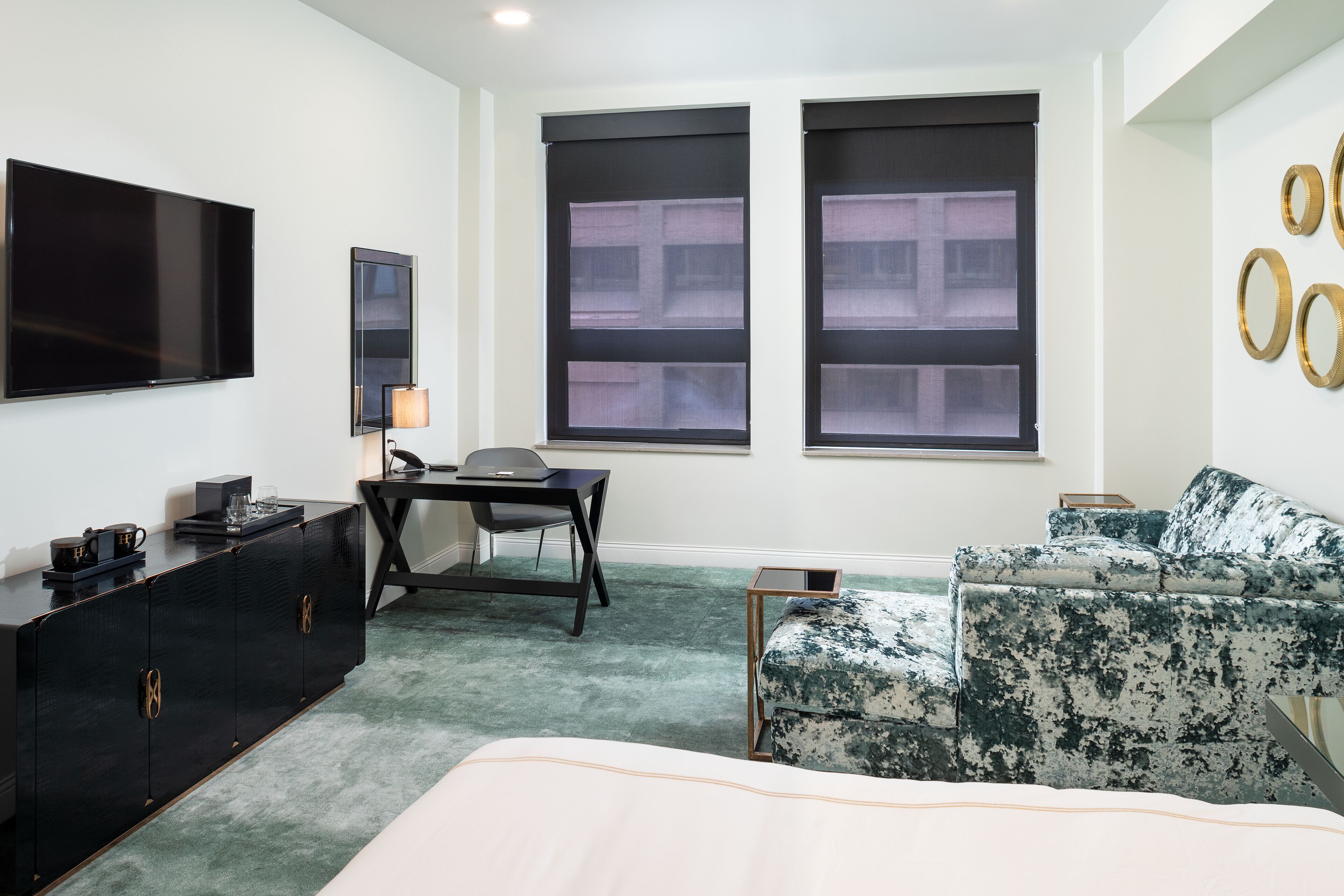 A hotel room with a bed, a desk, a TV, and a sofa.