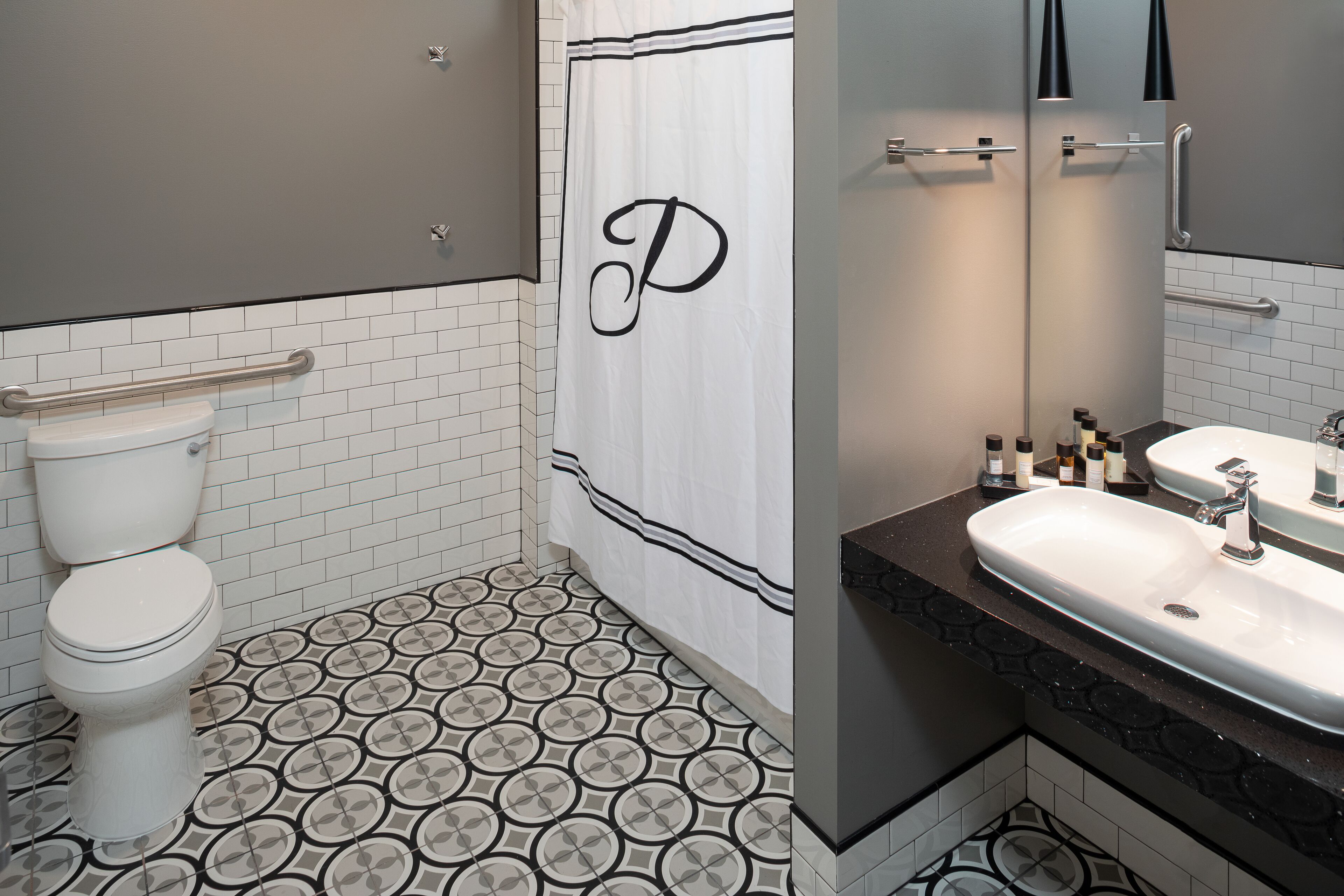 A bathroom with a toilet, a sink, and a shower curtain with a letter 'P' on it.