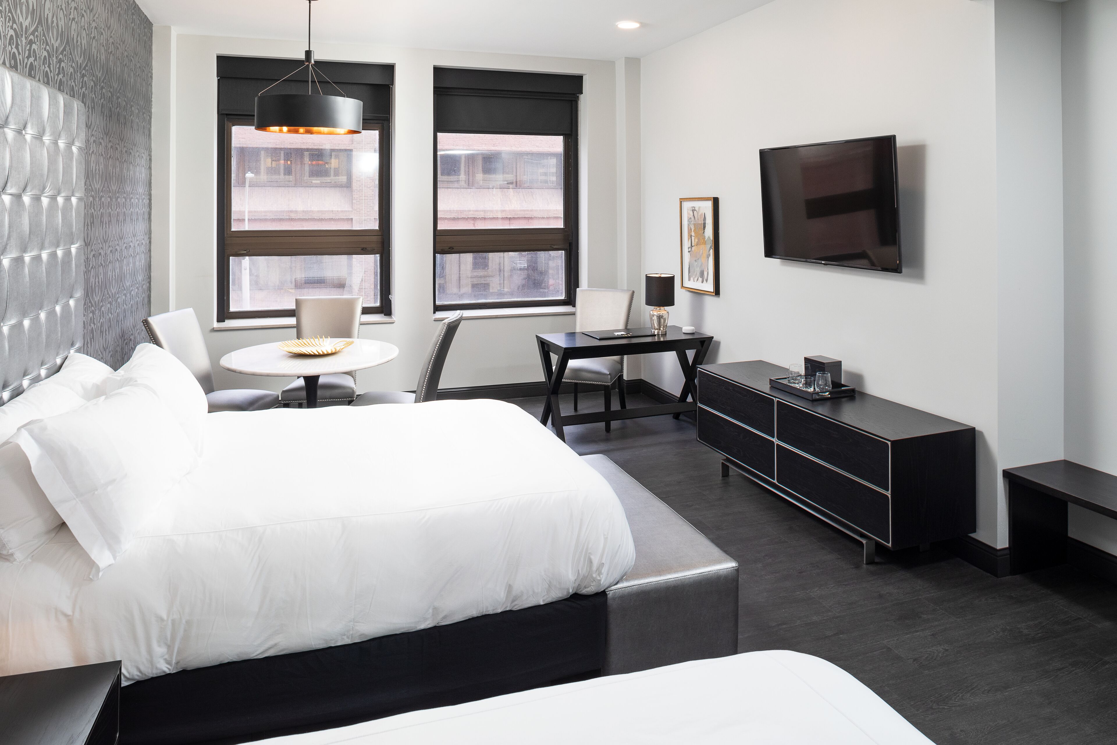 Une chambre d’hôtel moderne dotée d’un grand lit, d’un bureau, d’une chaise, d’une télévision et d’une fenêtre donnant sur la ville.