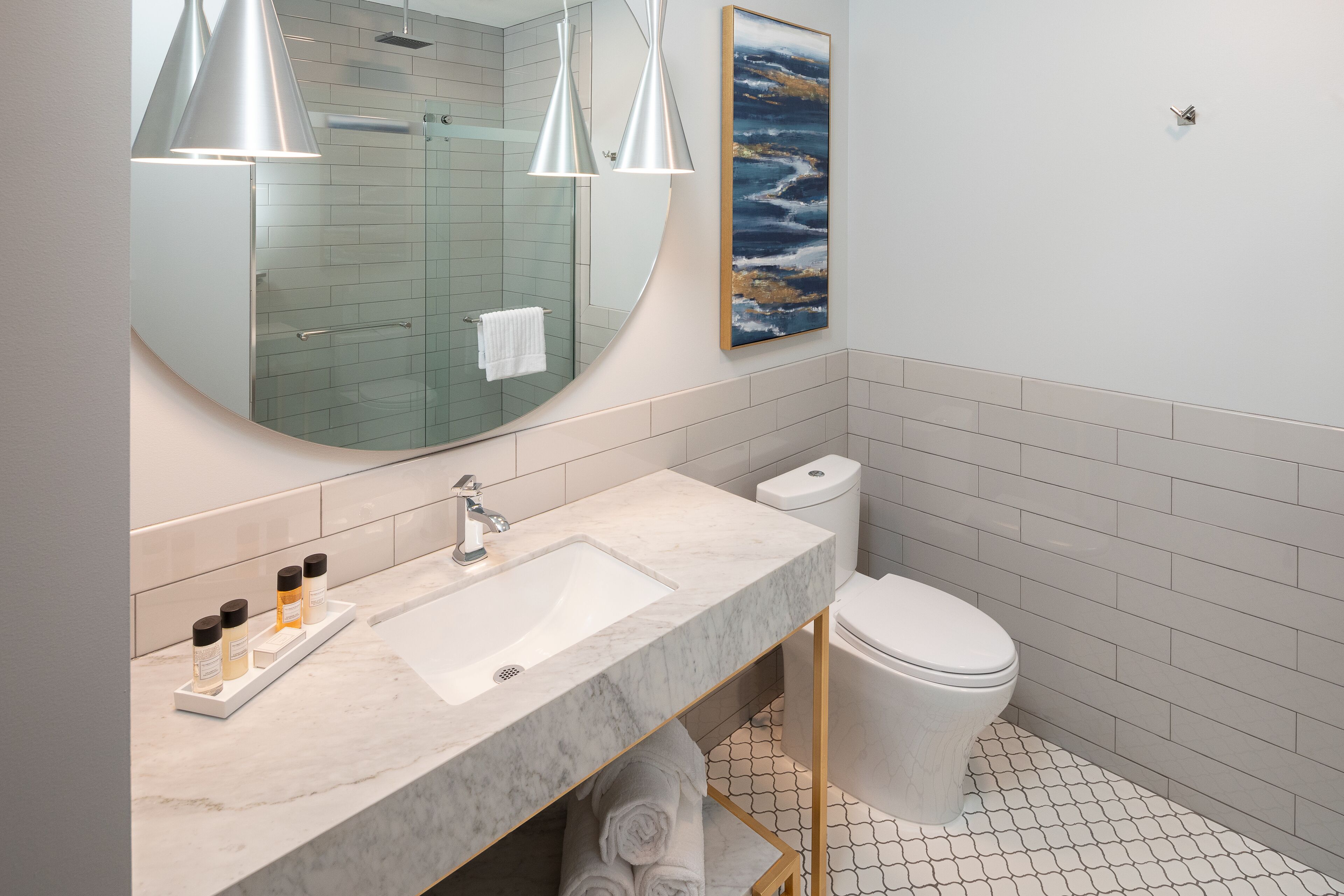 Un baño moderno con lavamanos de mármol, un espejo grande, cabina de ducha de vidrio y un inodoro.
