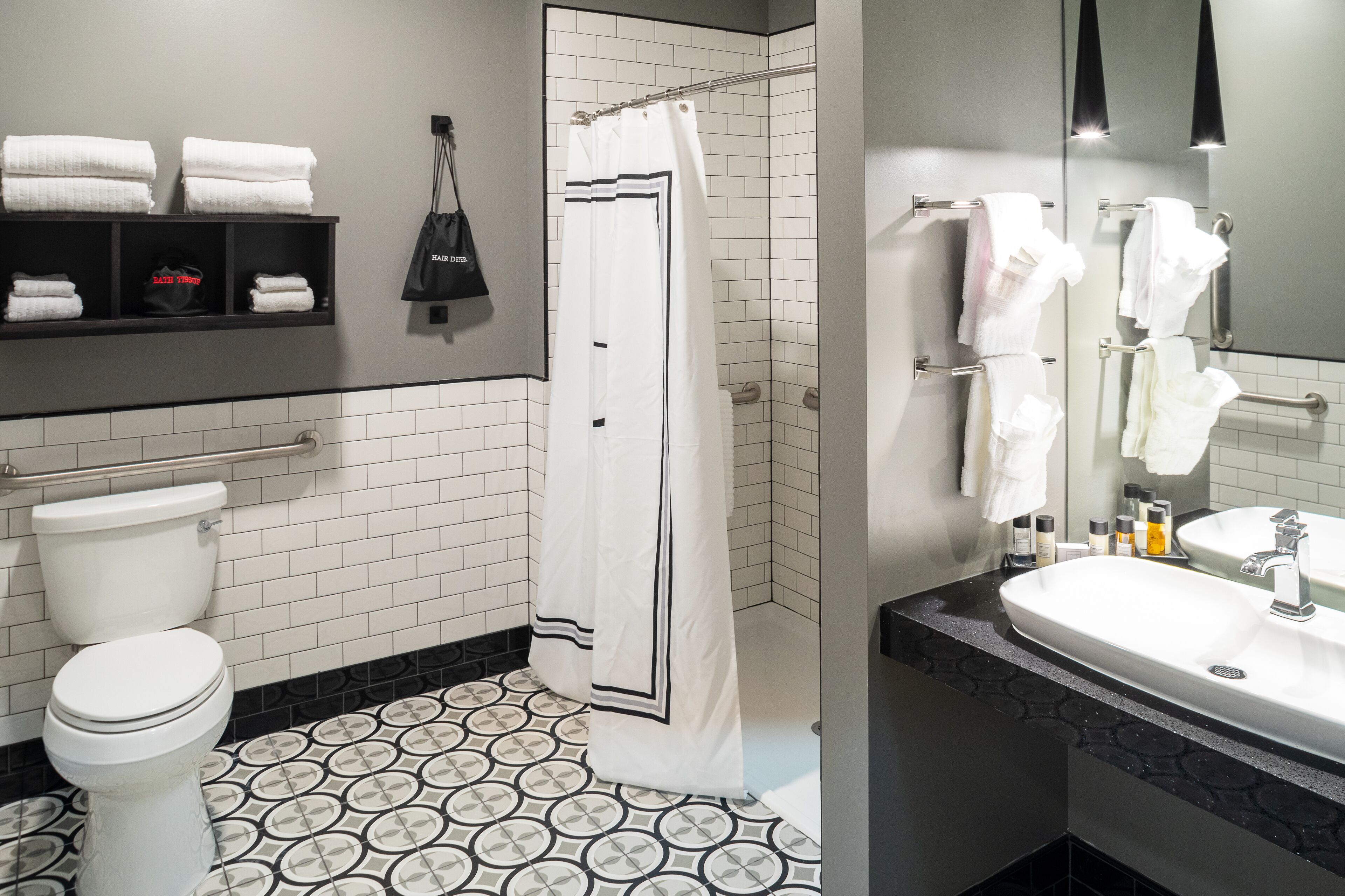 A modern bathroom with a toilet, shower, and sink. There are towels and toiletries on the counter.