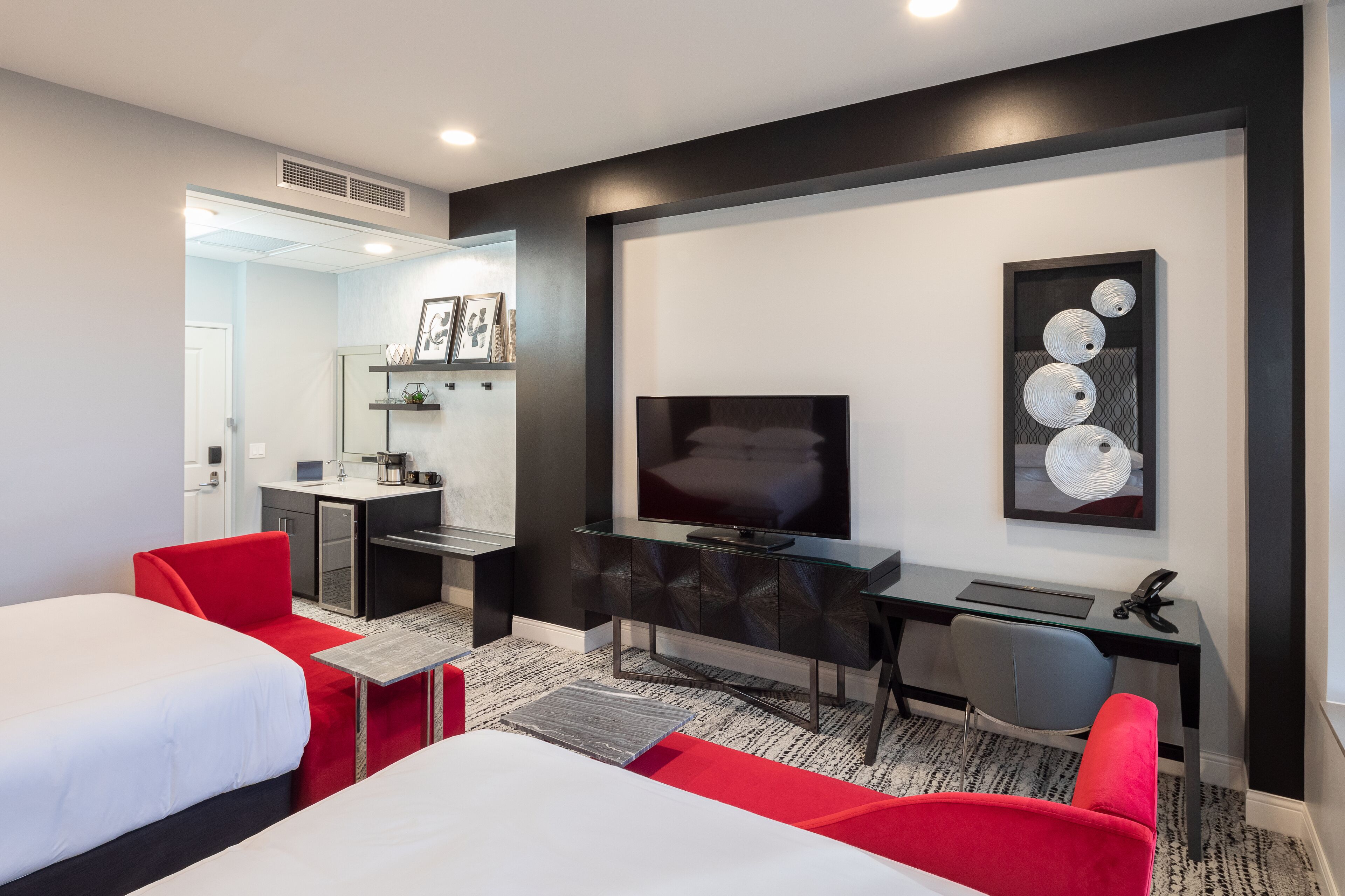 Une chambre d’hôtel moderne équipée de deux lits, d’un bureau, d’une télévision et d’une petite kitchenette.