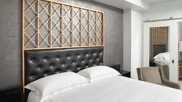 Un dormitorio moderno con cabecera capitonada, diseño de paneles de madera sobre la cama y una paleta de colores neutros.