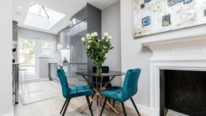 Une cuisine moderne avec une porte vitrée donnant sur un balcon, un coin repas avec une table ronde et des chaises de couleur turquoise, et une cheminée.