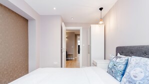 Une chambre à coucher moderne avec un grand lit, une tête de lit grise et une table de chevet.