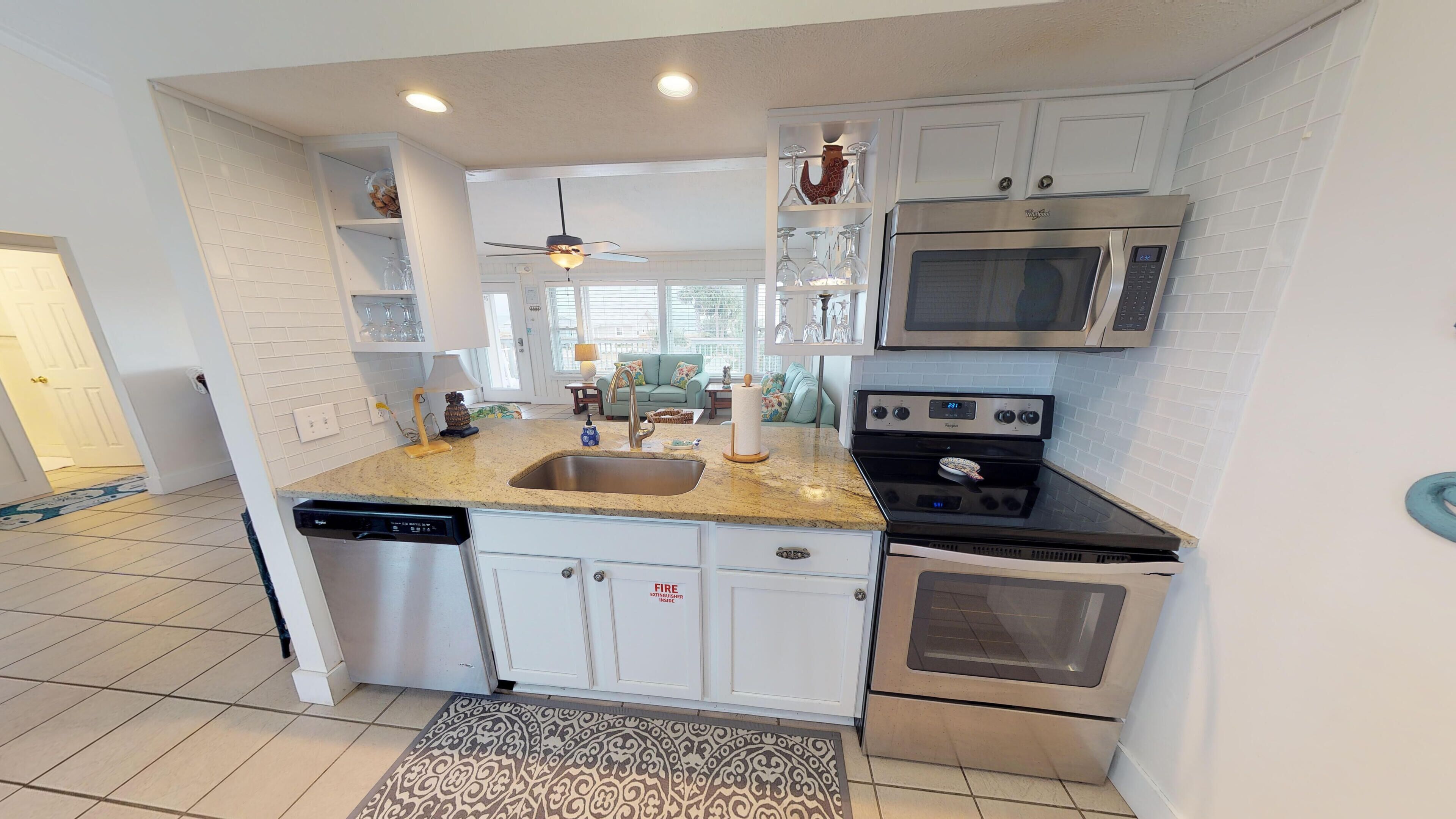 A modern kitchen with white cabinetry, a granite countertop, stainless steel appliances, and a built-in microwave.