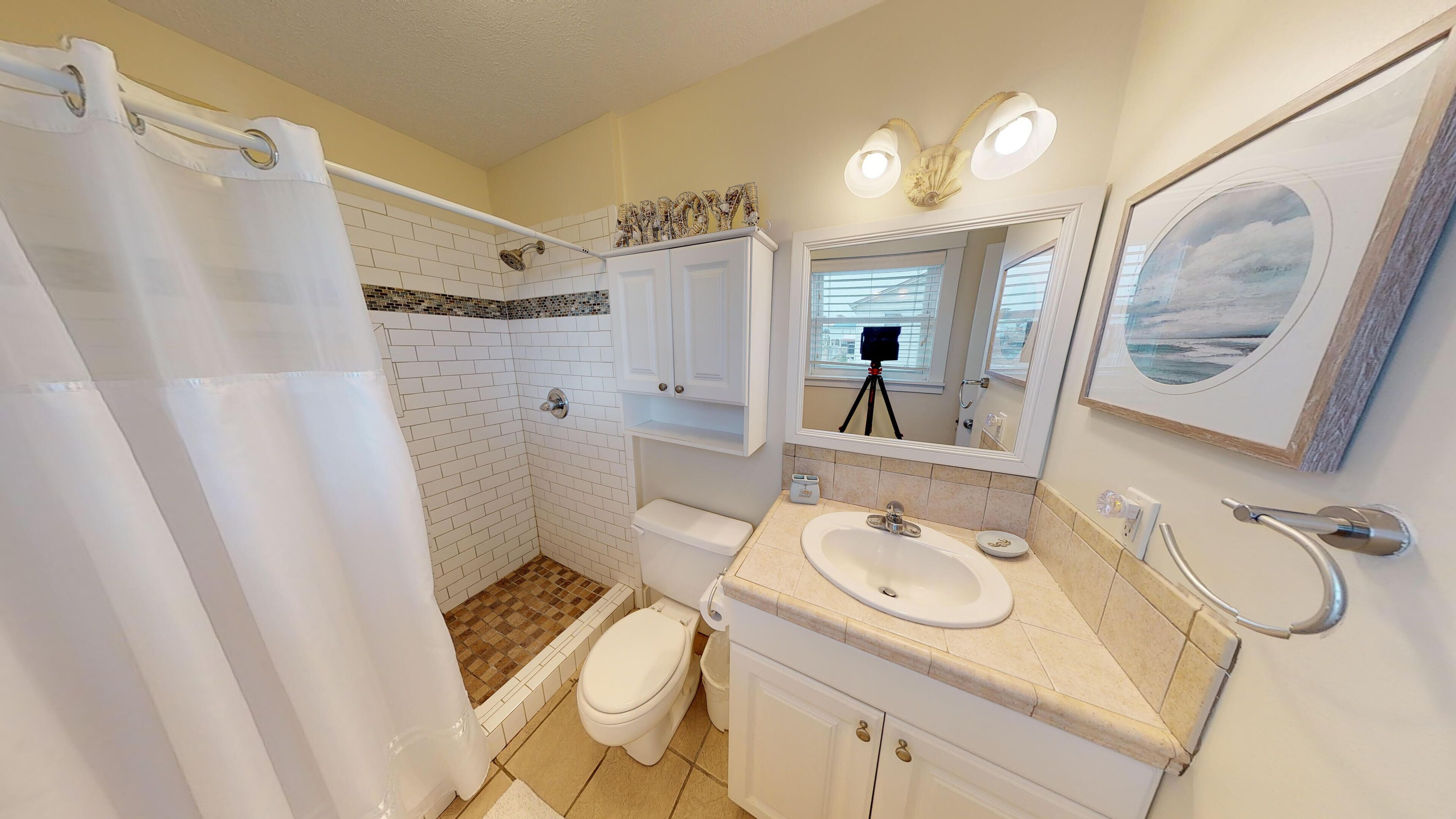 Une salle de bain équipée d’une douche, de toilettes, d’un lavabo et d’un meuble-lavabo.