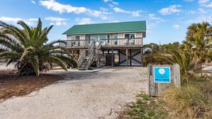 A two-story beachfront house with a green roof, a balcony, and a staircase leading to the upper level. - Family Friendly, Easy Beach Access Across the Street! (St. George Island)