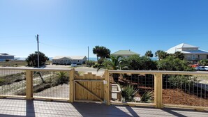 A gated entrance to a residential area with houses and a beach in the background. - Family Friendly, Easy Beach Access Across the Street! (St. George Island)