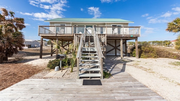 A wooden deck leading to a beach house with a green roof, a staircase, and a view of the beach. - Family Friendly, Easy Beach Access Across the Street! (St. George Island)