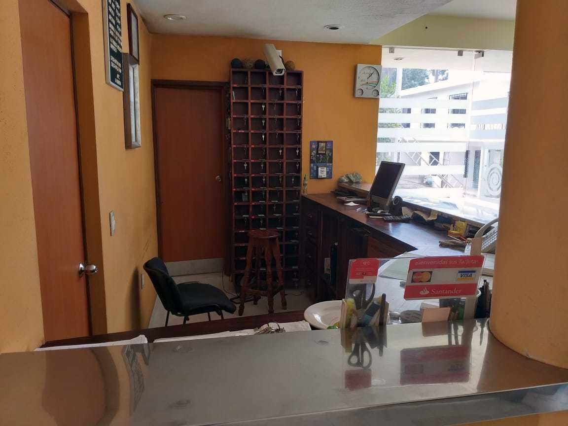 Een receptiegedeelte met een balie, stoelen, een sleutelhouder en uitzicht op het exterieur.