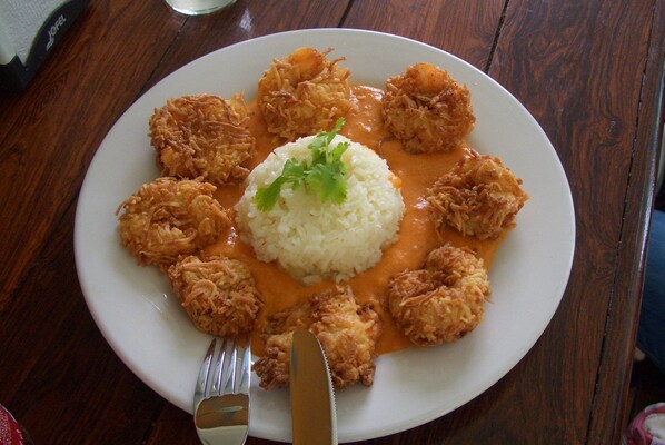 A plate of fried chicken with rice and sauce on a wooden table.