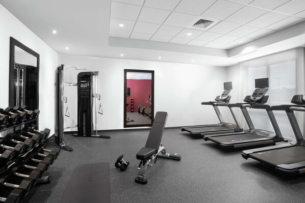 Un gimnasio moderno con cintas de correr, mancuernas y máquinas de pesas.