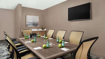 A conference room with a long table, chairs, a TV, and water bottles.