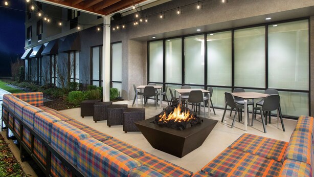 An outdoor patio area with seating, a fire pit, and tables and chairs.
