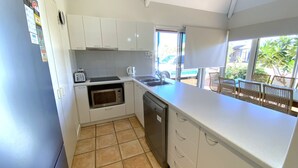 Una cocina compacta con armarios blancos, microondas, tostadora y lavavajillas.