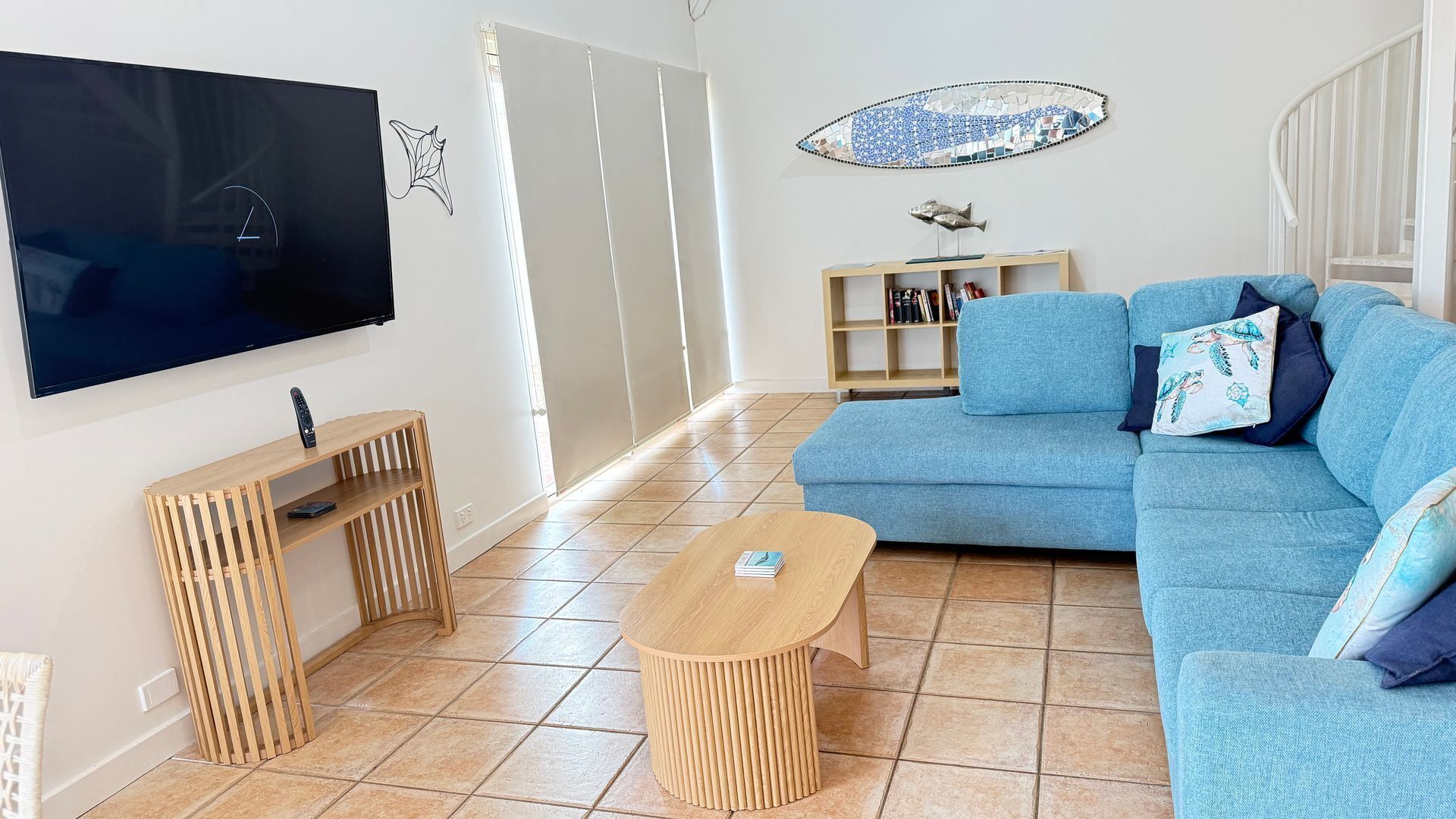 Un salon comprenant un téléviseur, un canapé, une table basse et une bibliothèque.