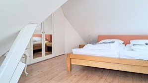 Un dormitorio con cama de madera, armario y techo inclinado.