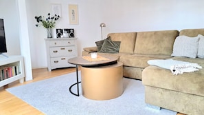 Een woonkamer met een bank, een salontafel, een boekenkast en een kast.