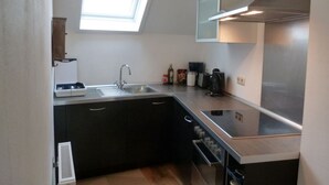 Una cocina moderna con tragaluz, electrodomésticos de acero inoxidable y armarios oscuros.