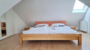 Een slaapkamer met een houten bed, twee nachtkastjes, een radiator en een dakraam.