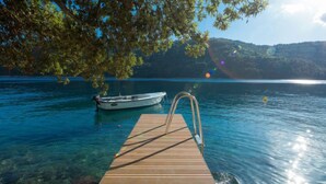 A wooden dock extending into a clear lake with a boat moored at the end. - Vlastelini II by Interhome (Labin)