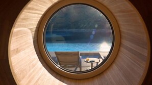 A circular window with a view of a pool and lounge chairs. - Vlastelini II by Interhome (Labin)