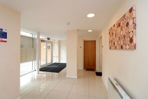 A clean, well-lit hallway with a wooden door, a radiator, and a wall-mounted artwork.