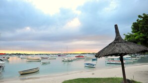 A marina with boats docked, a thatched umbrella, and a beach. - New apartment in Pereybere (100 mt from the beach) (Pereybere)